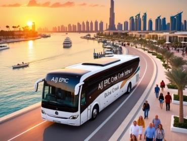 An AJ EPIC Mercedes bus driving near Dubai Creek Harbour, with boats on the water and palm trees lining the sunset-lit promenade.